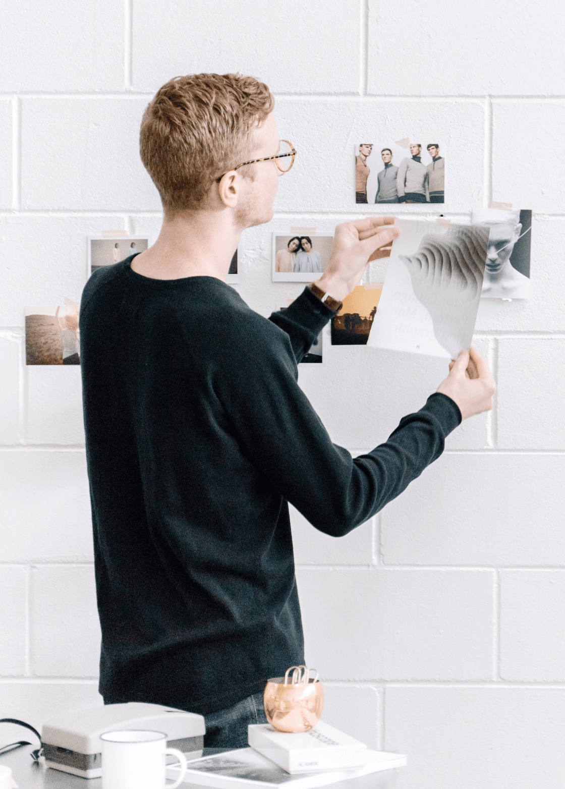 Man hanging photos on the white wall